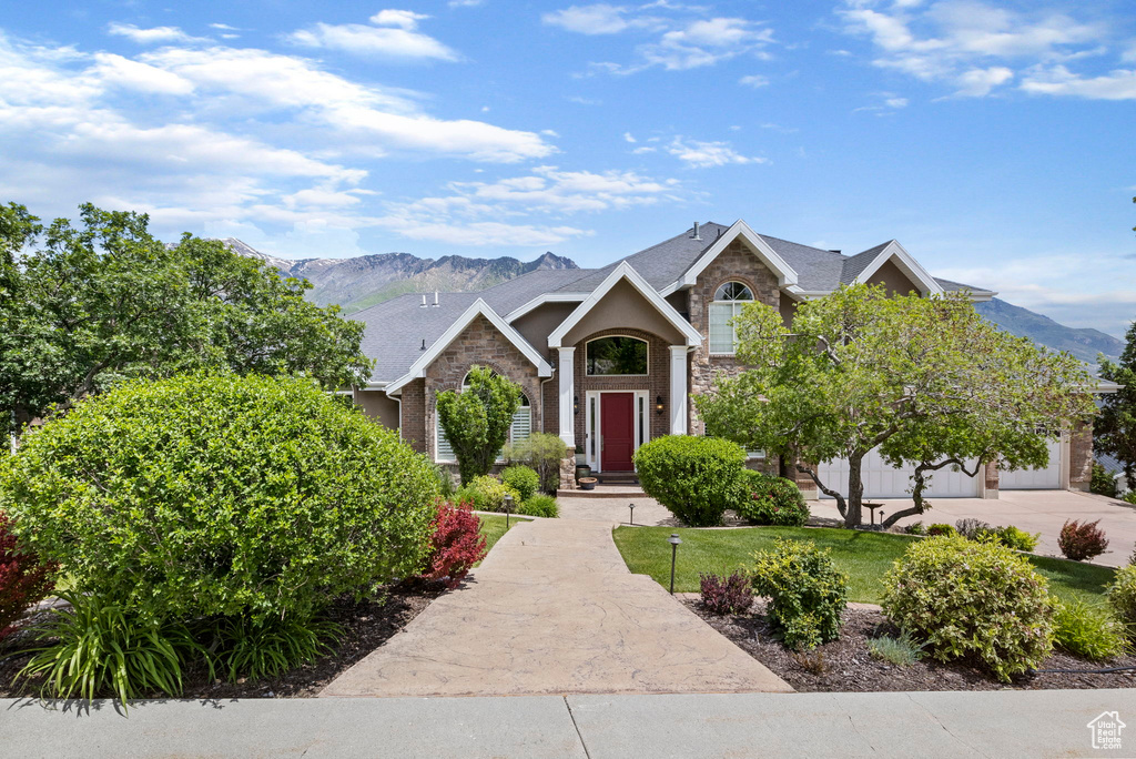 View of front of property featuring a mountain view, a front yard, and stone siding