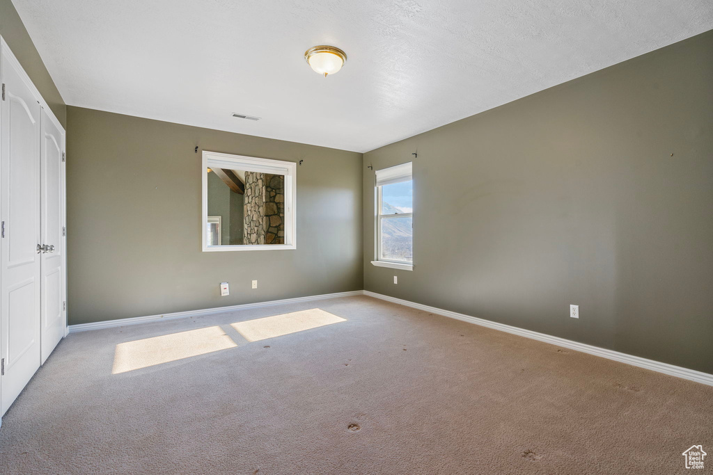 Spare room featuring baseboards, carpet flooring, and visible vents