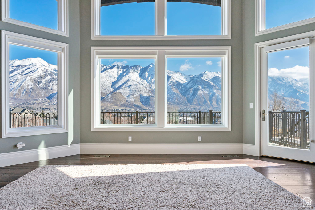 Interior space featuring baseboards, a mountain view, wood finished floors, and a high ceiling