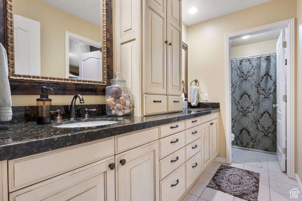 Full bath featuring tile patterned flooring, vanity, toilet, a shower with shower curtain, and baseboards