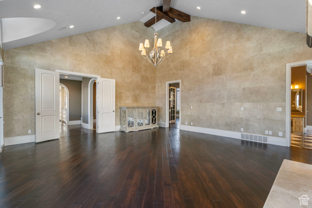 Unfurnished living room with baseboards, a notable chandelier, high vaulted ceiling, and hardwood / wood-style flooring