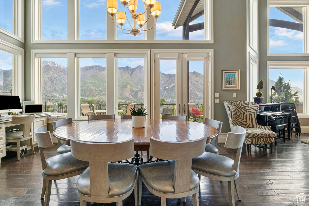 Dining space featuring a chandelier, plenty of natural light, dark wood-type flooring, and a towering ceiling