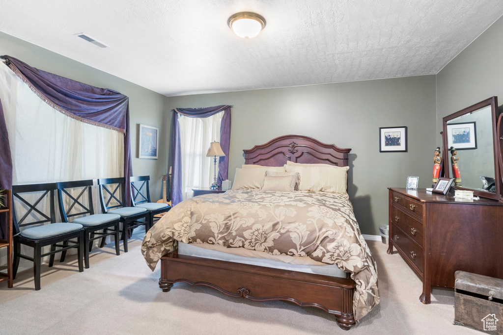 Carpeted bedroom featuring visible vents and a textured ceiling