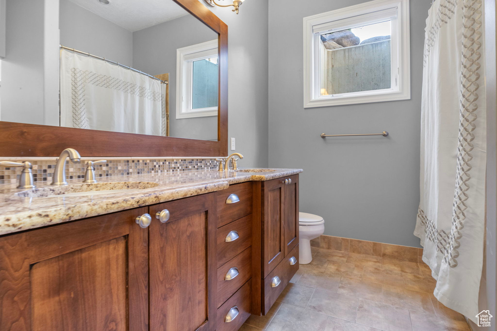 Full bath featuring double vanity, baseboards, a sink, and a wealth of natural light