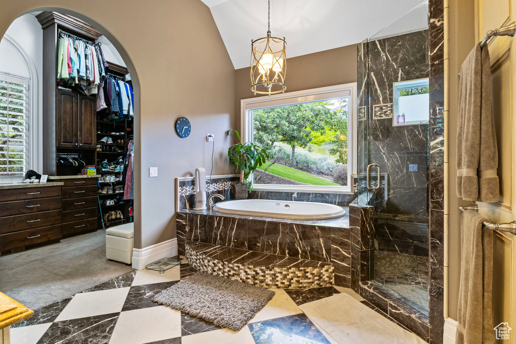 Bathroom with a chandelier, a marble finish shower, baseboards, vaulted ceiling, and a garden tub