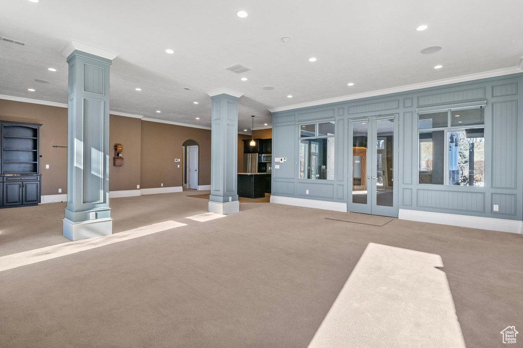 Exercise room featuring ornate columns, crown molding, and light carpet