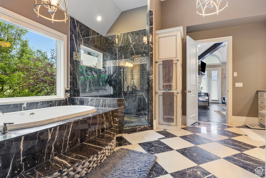 Full bath with an inviting chandelier, lofted ceiling, baseboards, a bath, and a marble finish shower