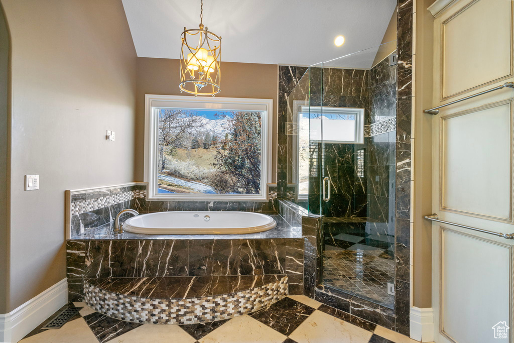 Bathroom featuring a notable chandelier, marble finish floor, baseboards, a garden tub, and a stall shower