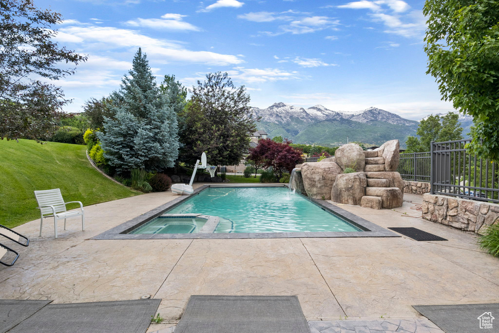 View of pool with fence, a mountain view, a pool with connected hot tub, and a patio area