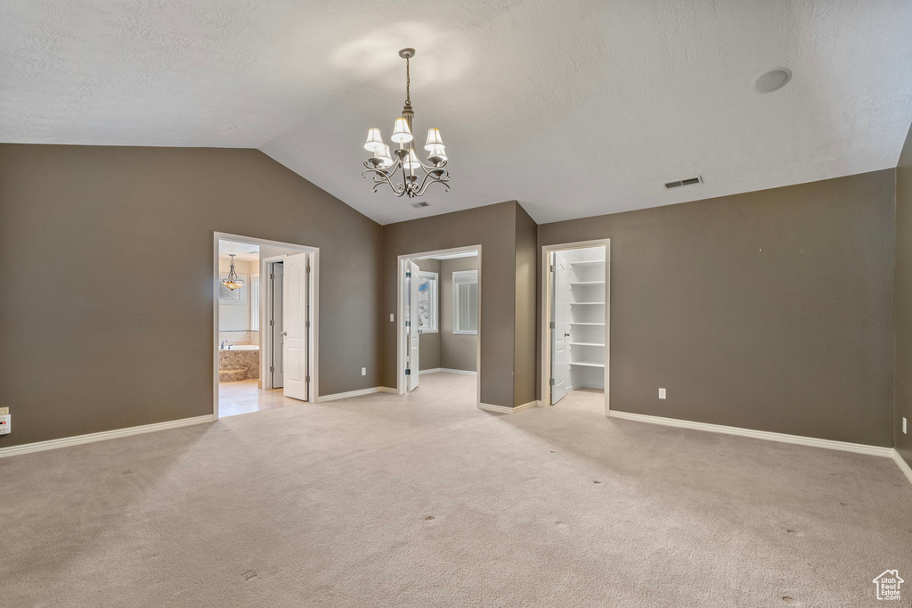 Empty room featuring visible vents, baseboards, a chandelier, and light carpet