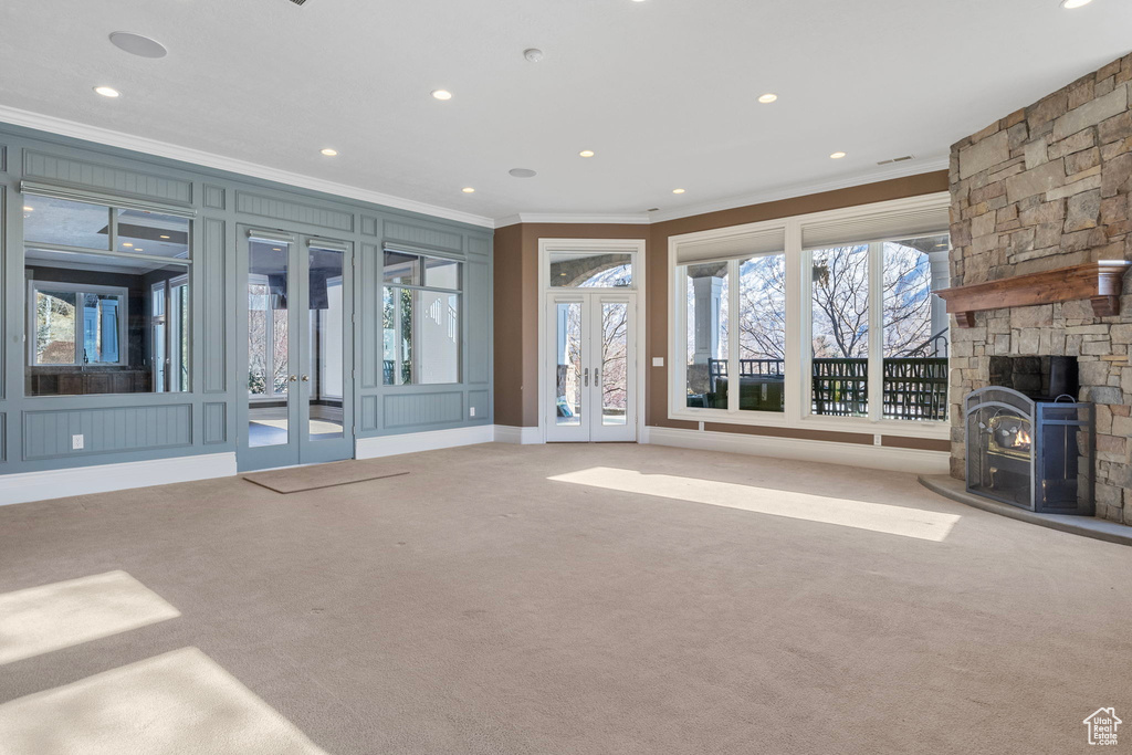 Unfurnished living room featuring french doors, crown molding, a fireplace, carpet floors, and recessed lighting