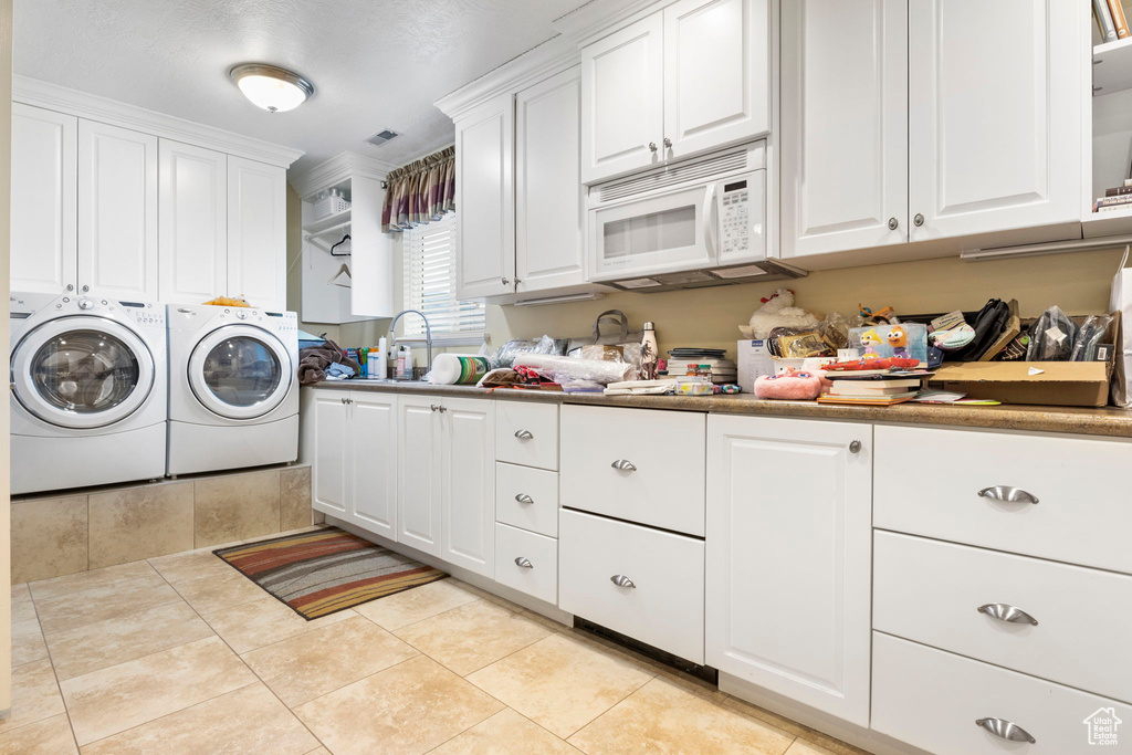 Laundry area with independent washer and dryer, light tile patterned flooring, cabinet space, a sink, and visible vents