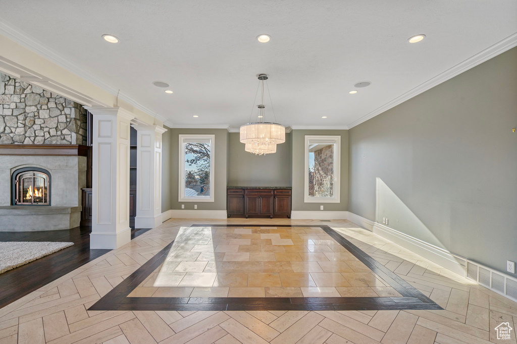 Interior space featuring a stone fireplace, recessed lighting, ornate columns, and an inviting chandelier