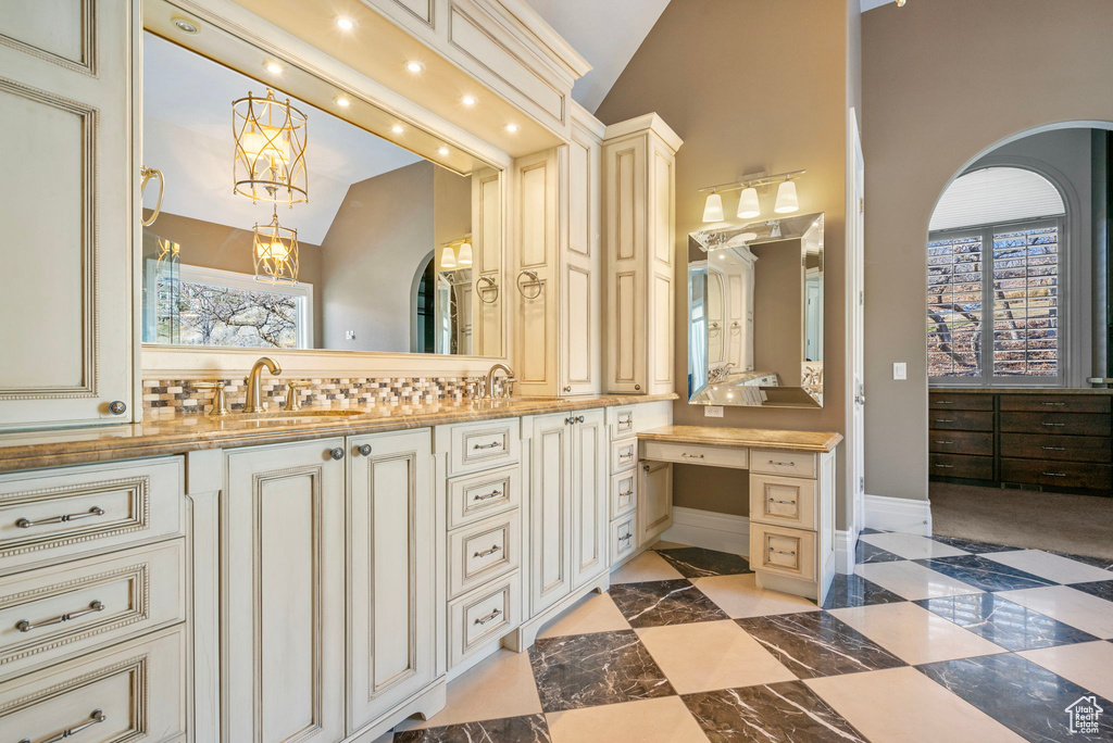 Full bath with double vanity, a sink, baseboards, and vaulted ceiling