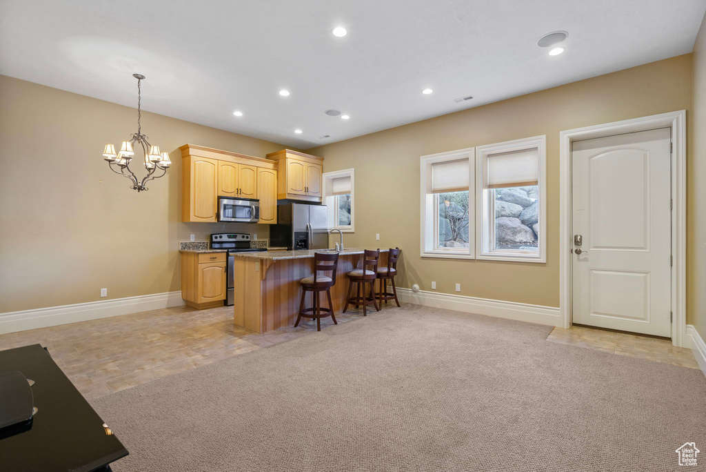 Kitchen with baseboards, appliances with stainless steel finishes, a breakfast bar, and an inviting chandelier