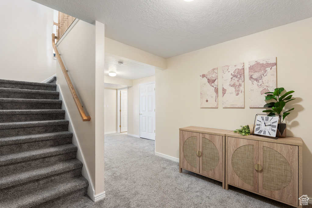 Staircase featuring baseboards, carpet flooring, and a textured ceiling
