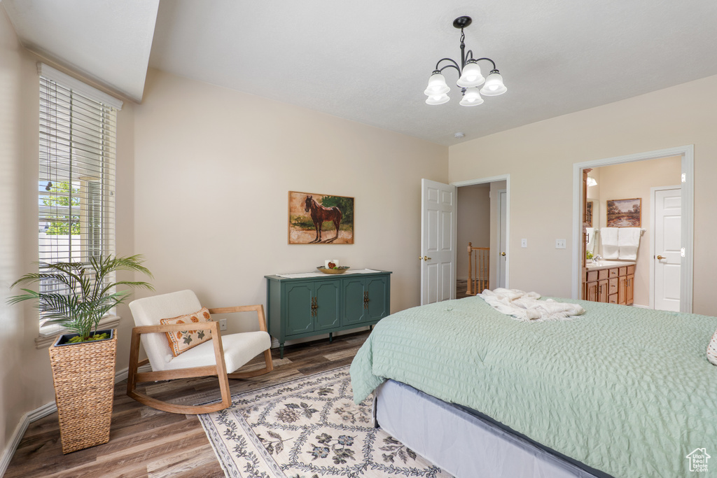 Bedroom featuring baseboards, ensuite bathroom, wood finished floors, and a chandelier