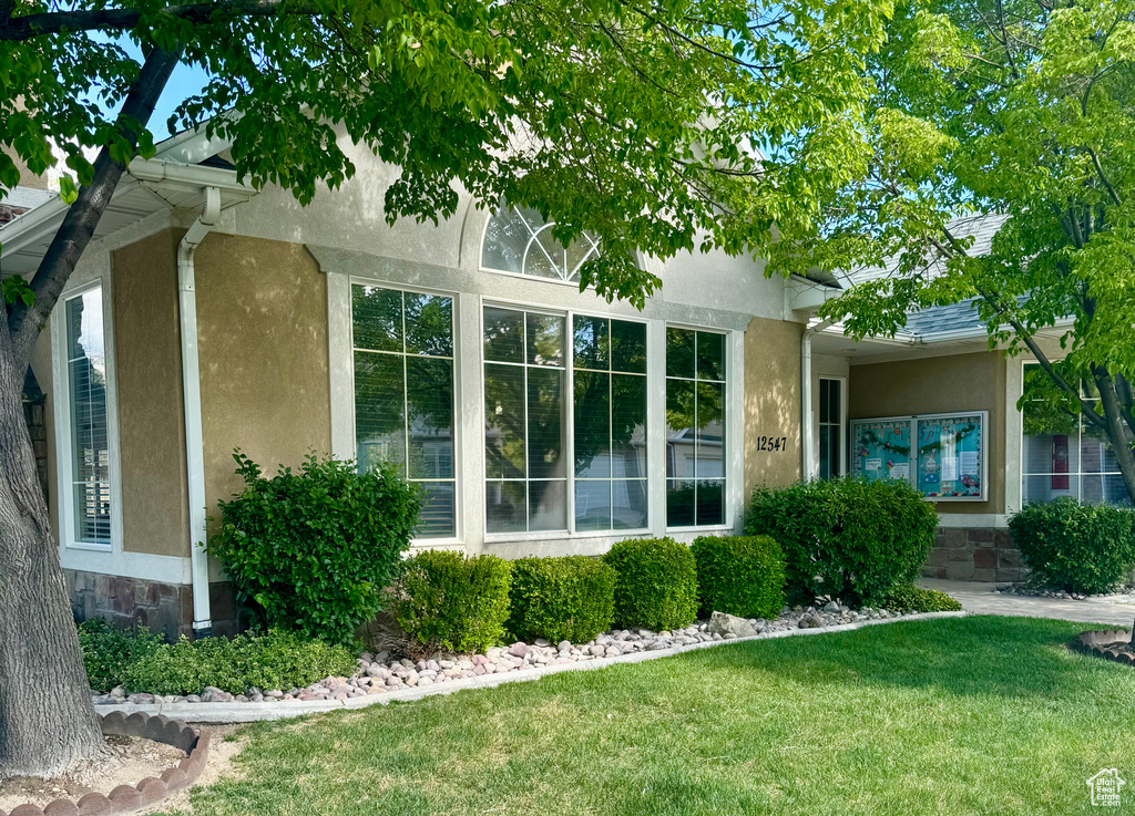 View of side of property with a lawn, stone siding, and stucco siding