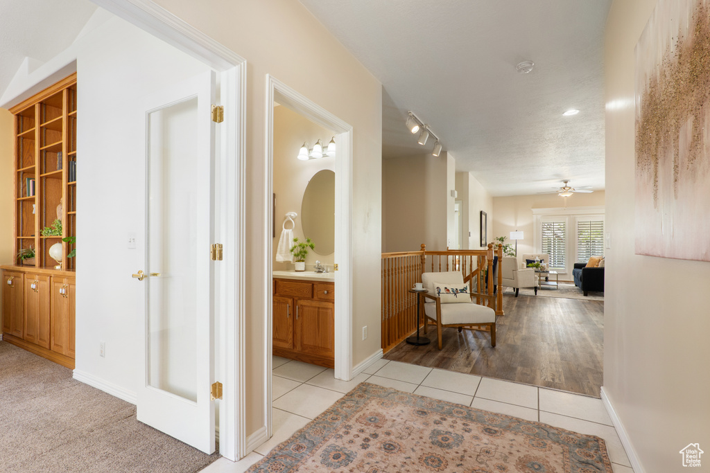 Hall with baseboards, a sink, and light tile patterned floors
