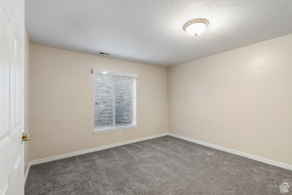 Spare room with visible vents, carpet flooring, baseboards, and a textured ceiling