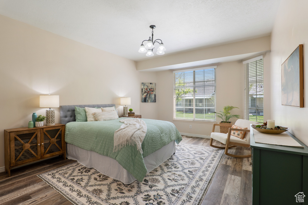 Bedroom featuring baseboards, a chandelier, and wood finished floors
