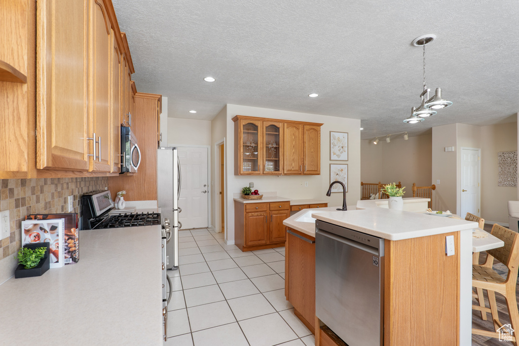 Kitchen with a sink, appliances with stainless steel finishes, a breakfast bar area, and light countertops