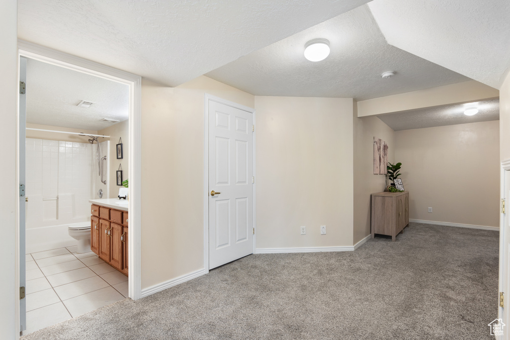 Basement with a textured ceiling, light colored carpet, and baseboards