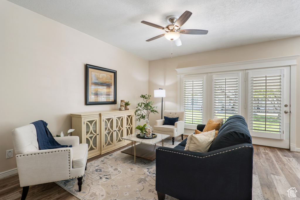 Living room featuring a healthy amount of sunlight, baseboards, ceiling fan, and wood finished floors