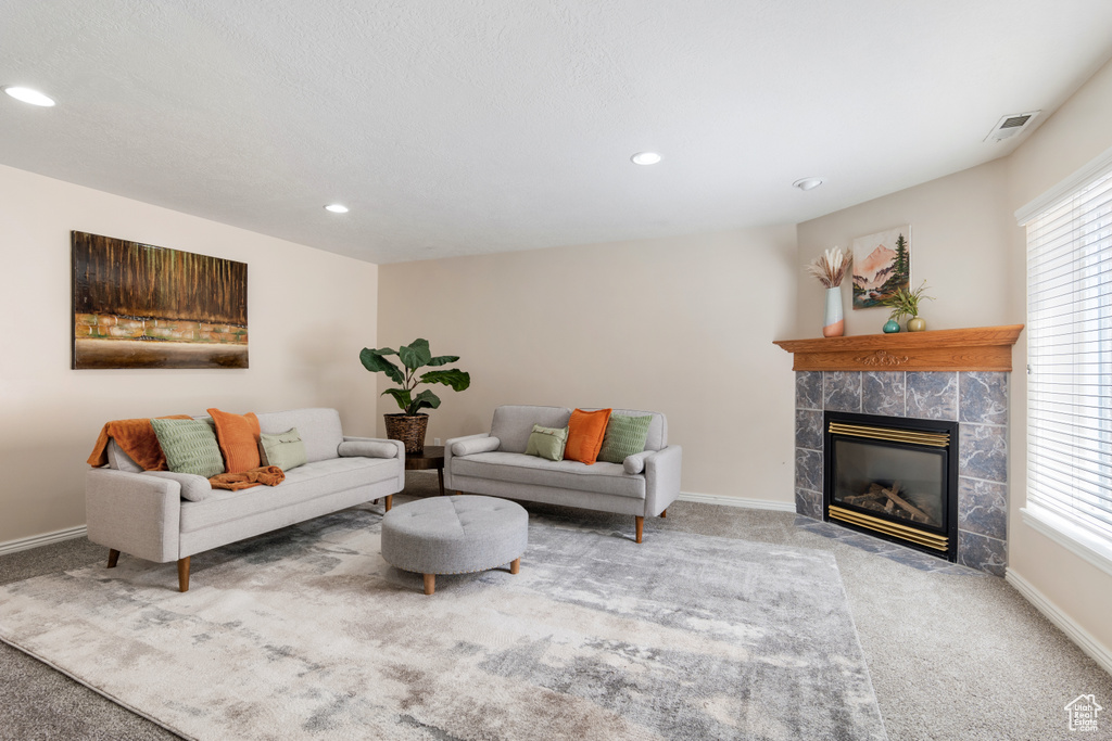 Living room with a wealth of natural light, carpet, a tile fireplace, and visible vents