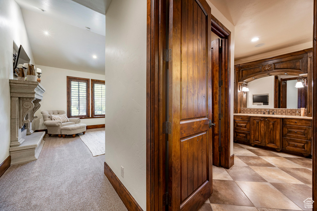 Hallway with recessed lighting, a sink, baseboards, and light colored carpet
