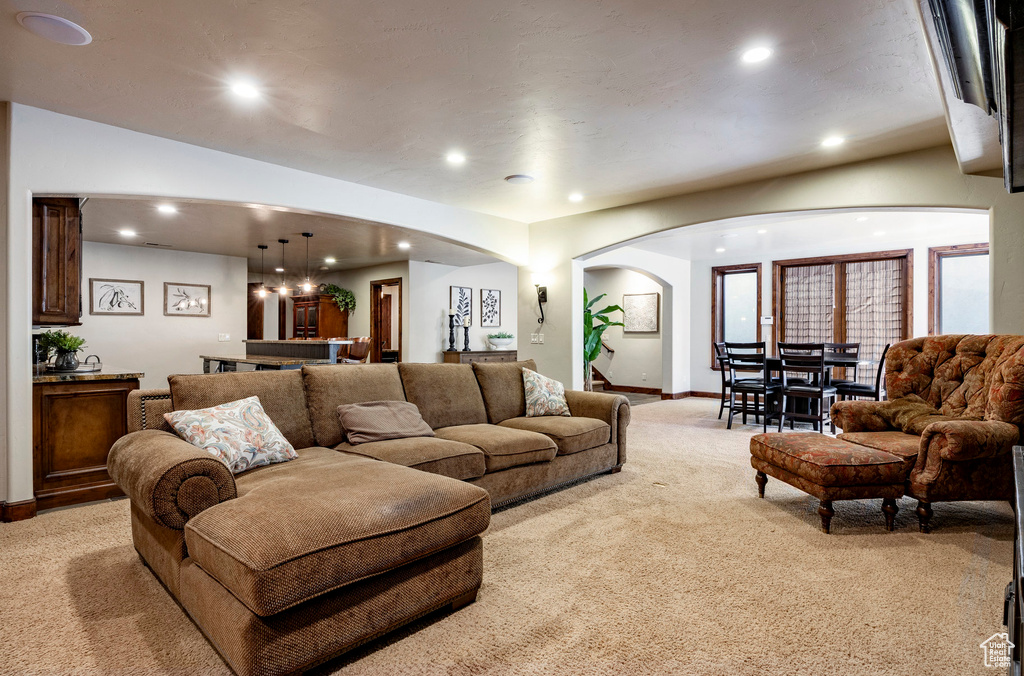 Living area with arched walkways, baseboards, light carpet, and recessed lighting