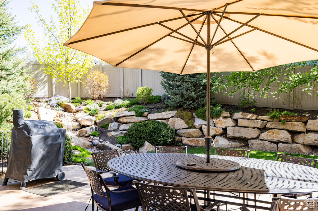 View of patio / terrace with fence, outdoor dining space, and a grill
