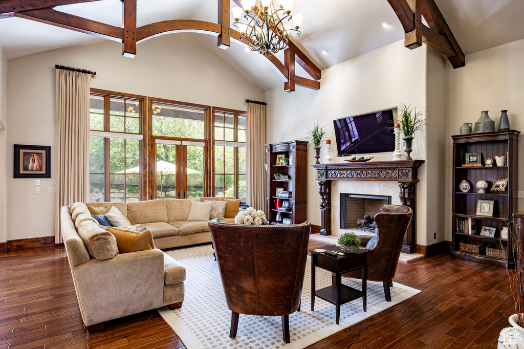 Living area featuring dark wood-style flooring, a premium fireplace, a chandelier, baseboards, and beamed ceiling