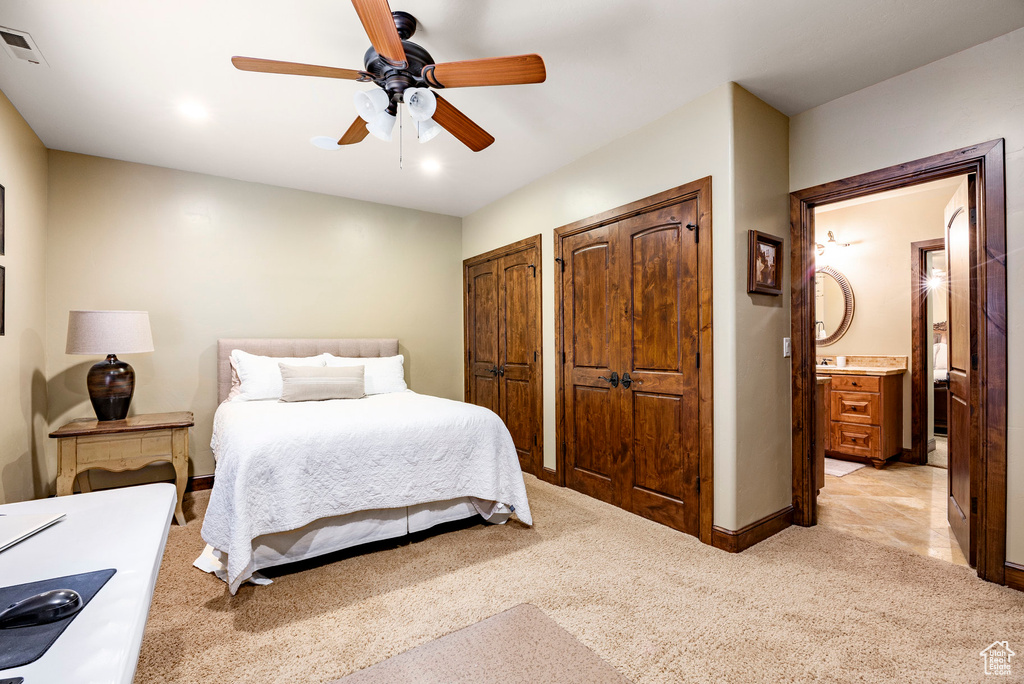 Bedroom featuring ceiling fan, light colored carpet, multiple closets, baseboards, and visible vents