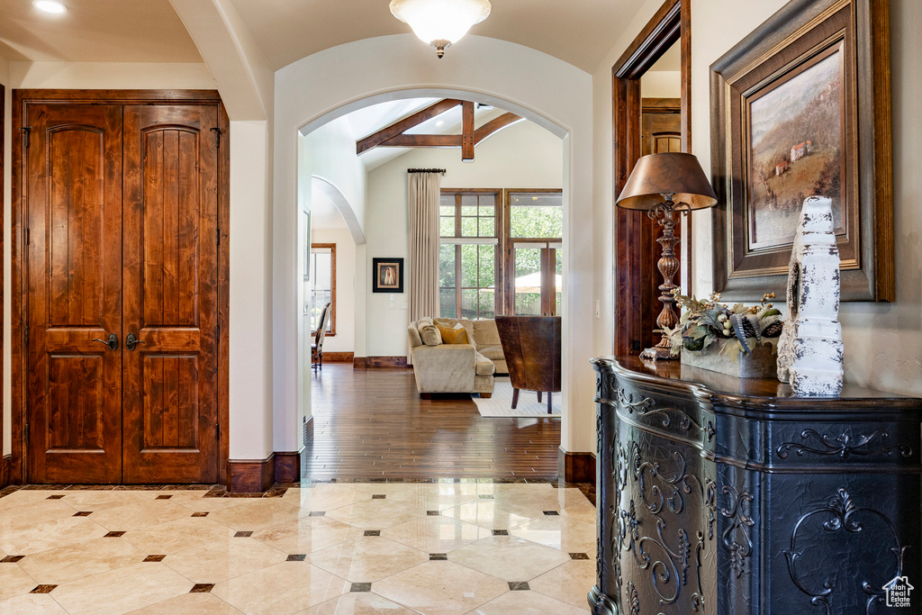 Foyer with baseboards, arched walkways, lofted ceiling, and light tile patterned floors