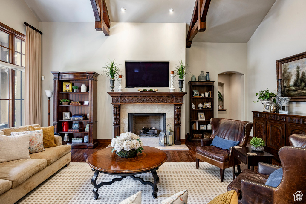 Living area featuring a high end fireplace, arched walkways, wood finished floors, and beamed ceiling