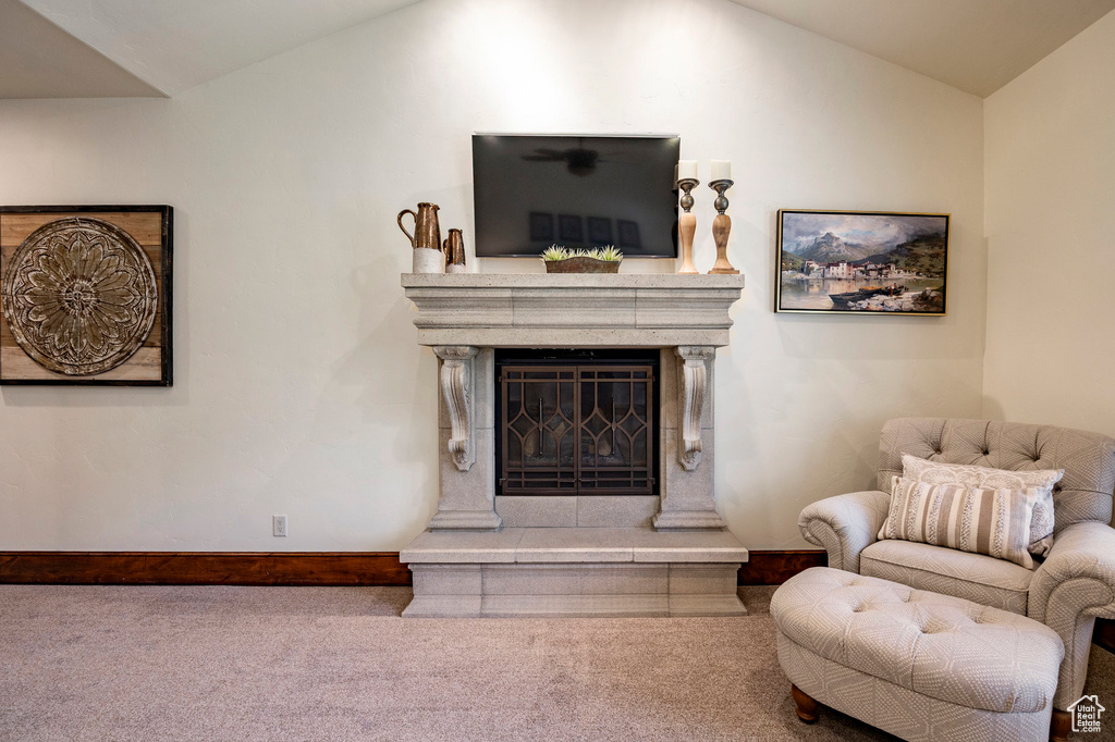 Carpeted living room with a glass covered fireplace, baseboards, and vaulted ceiling