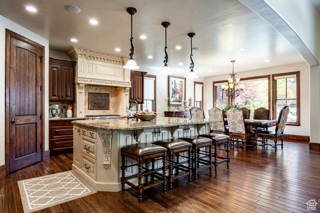Kitchen featuring baseboards, a large island, a breakfast bar area, and light stone countertops