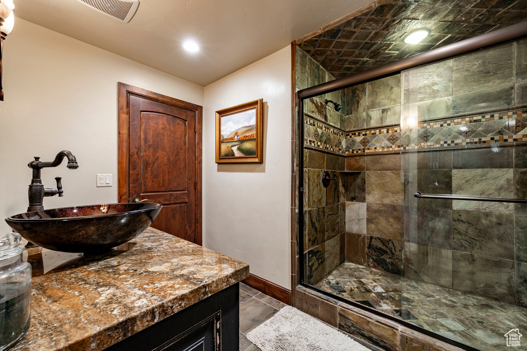 Full bathroom with vanity, baseboards, a stall shower, and visible vents