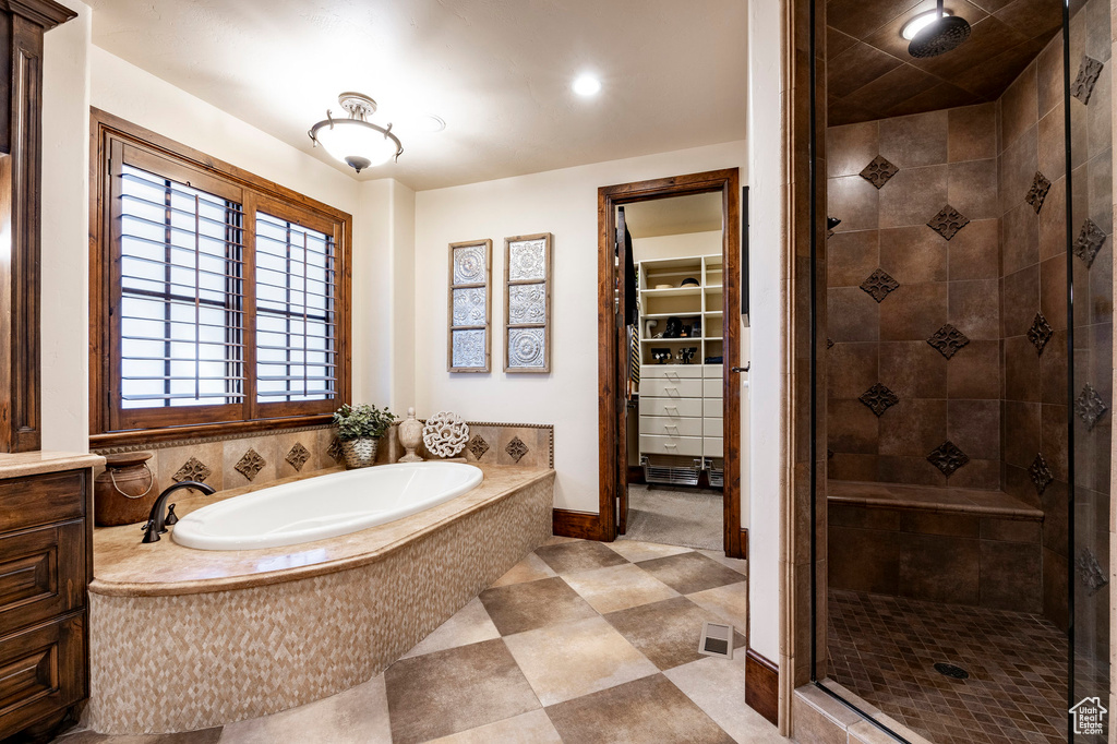 Full bath with tile patterned floors, a walk in closet, a bath, and a stall shower