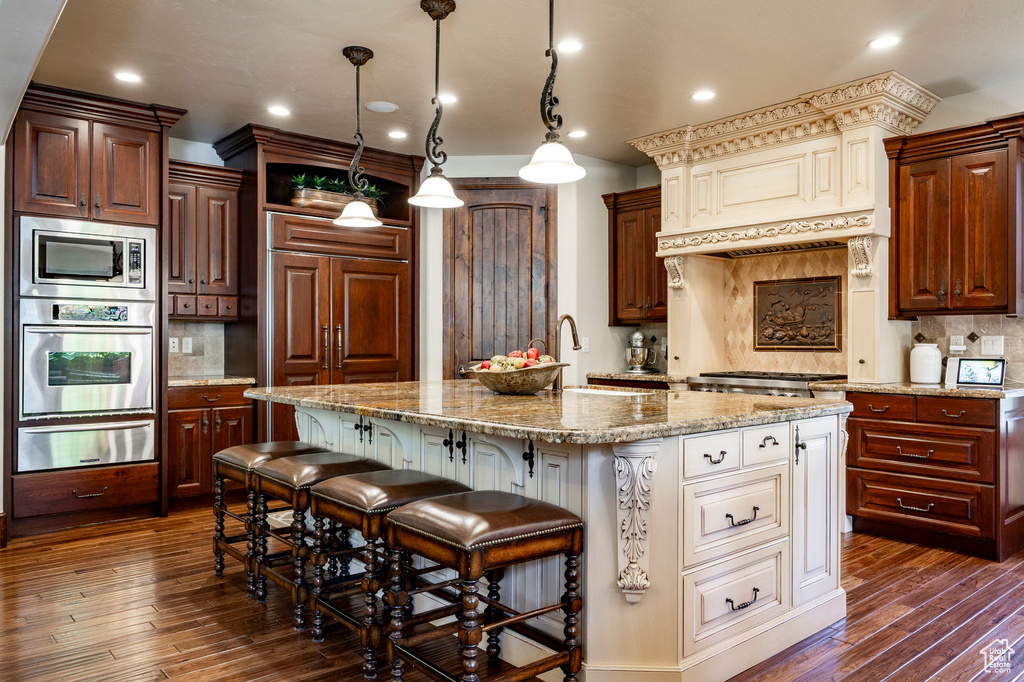 Kitchen featuring dark wood-type flooring, decorative backsplash, a warming drawer, and stainless steel appliances