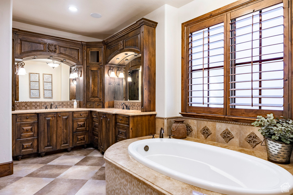 Full bath with double vanity, recessed lighting, a sink, and a bath