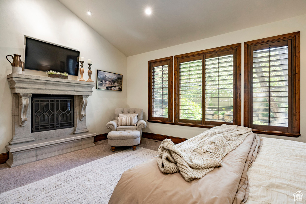 Carpeted bedroom with baseboards, a fireplace with raised hearth, recessed lighting, and lofted ceiling