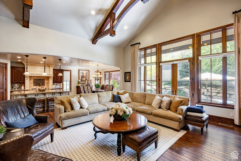 Living room featuring beamed ceiling, high vaulted ceiling, recessed lighting, dark wood finished floors, and a notable chandelier