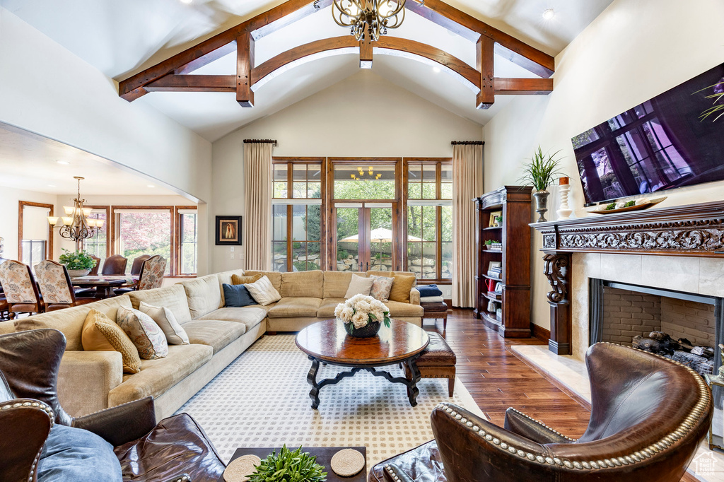 Living room featuring high vaulted ceiling, a chandelier, a tiled fireplace, recessed lighting, and wood finished floors