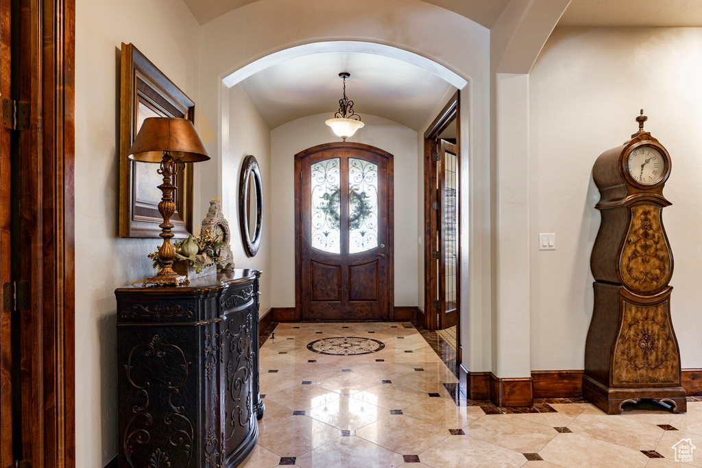 Entrance foyer with arched walkways, baseboards, and tile patterned flooring