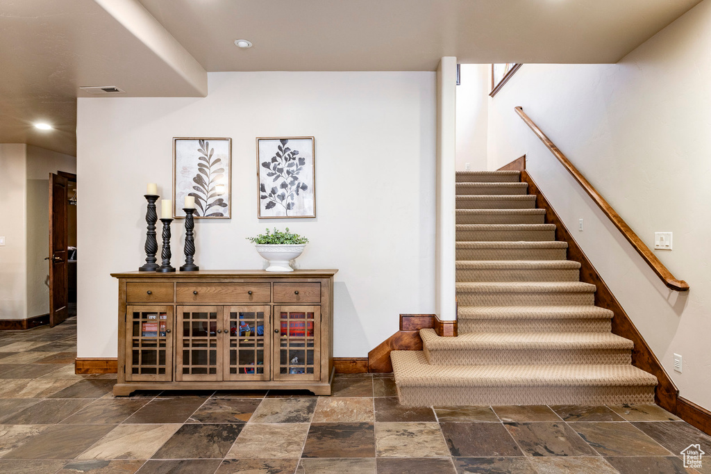 Stairway featuring stone tile floors, recessed lighting, baseboards, and visible vents