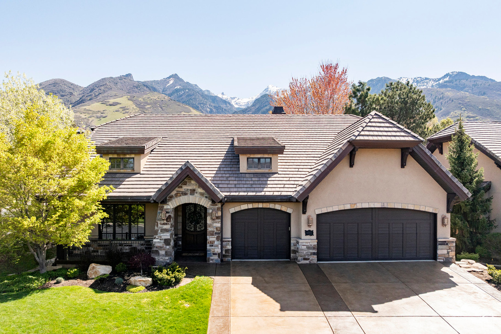 English style home with concrete driveway, a mountain view, and stone siding