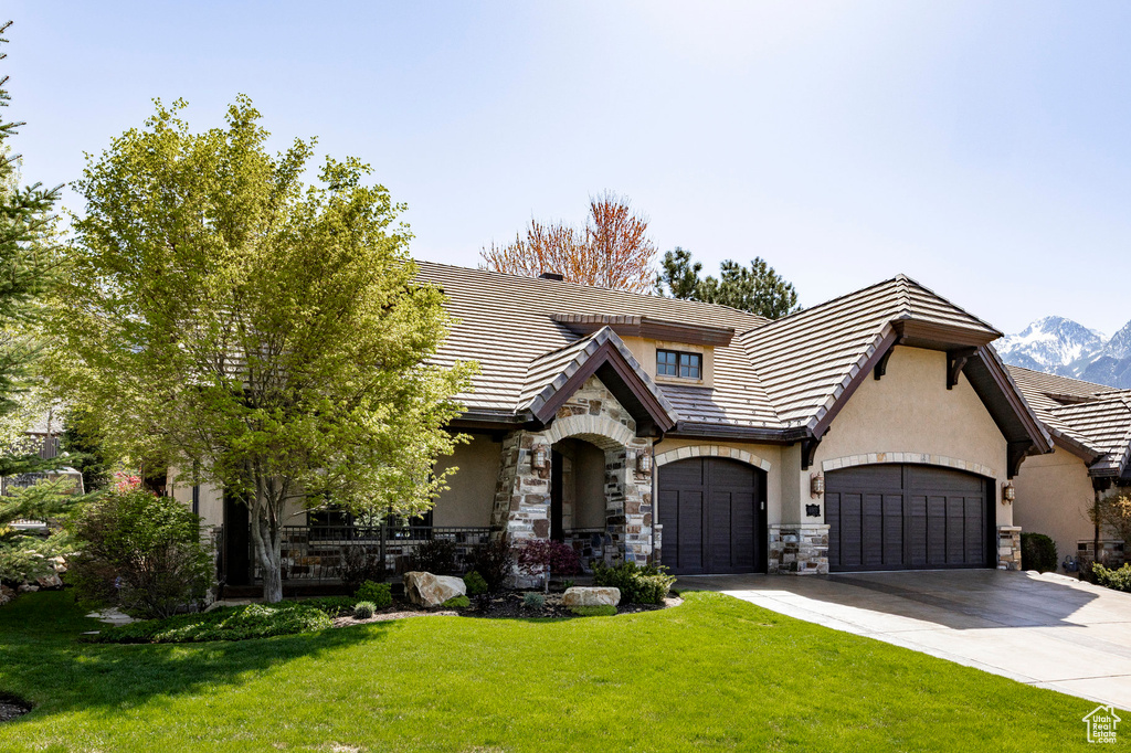 Tudor-style house featuring stucco siding, a front yard, and stone siding