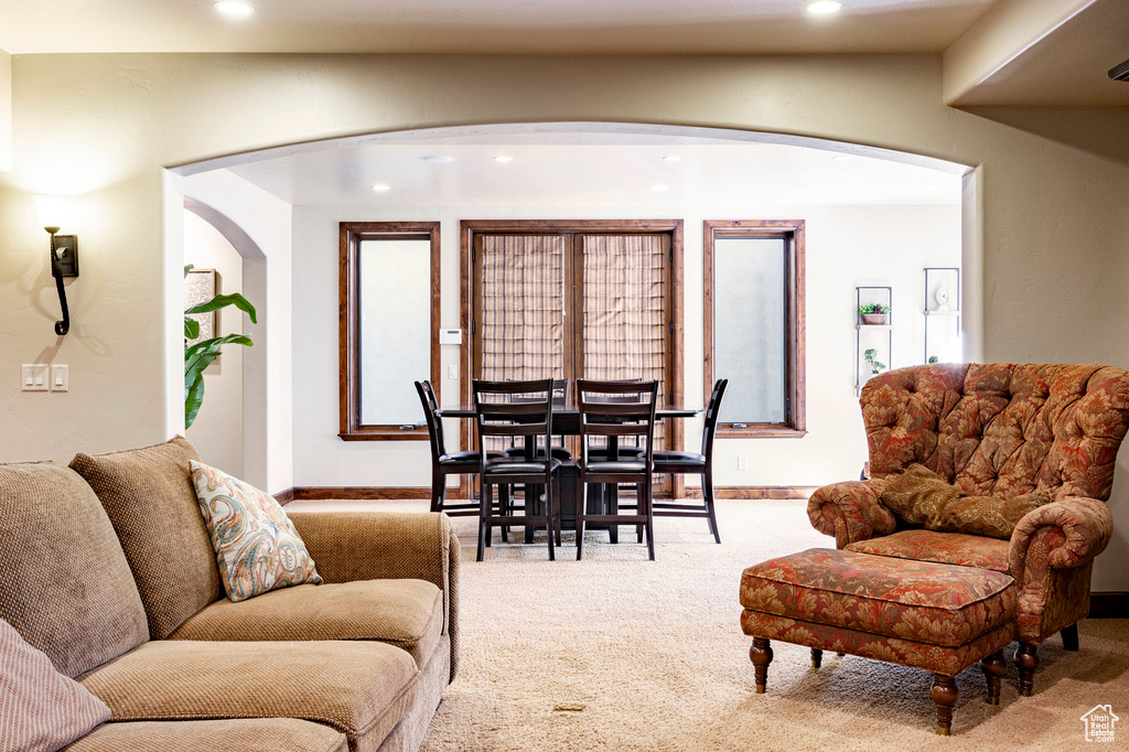 Carpeted living room featuring arched walkways, baseboards, and recessed lighting
